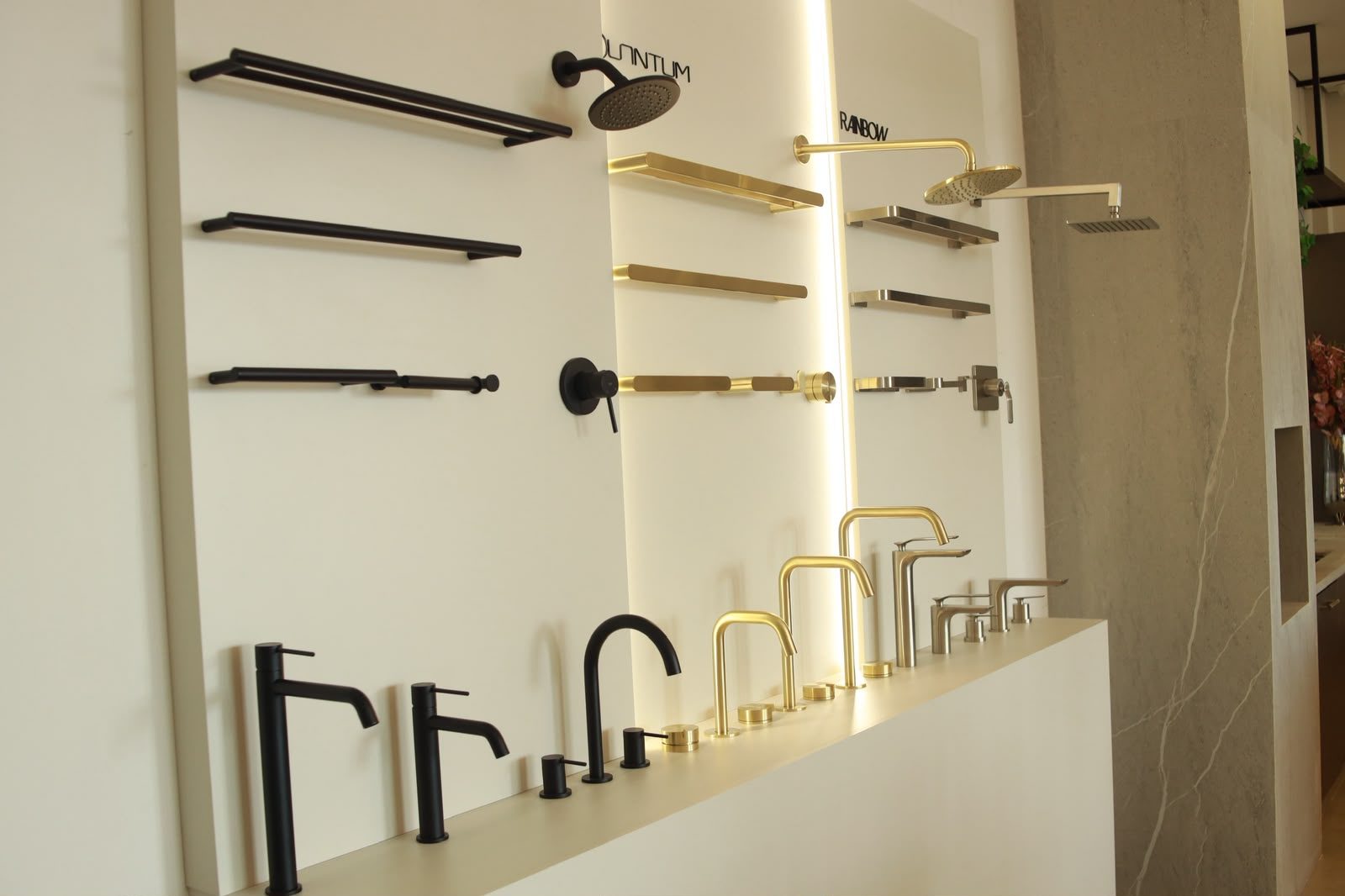 Parede de metais em preto fosco, dourado e inox escovado no showroom da KMAC